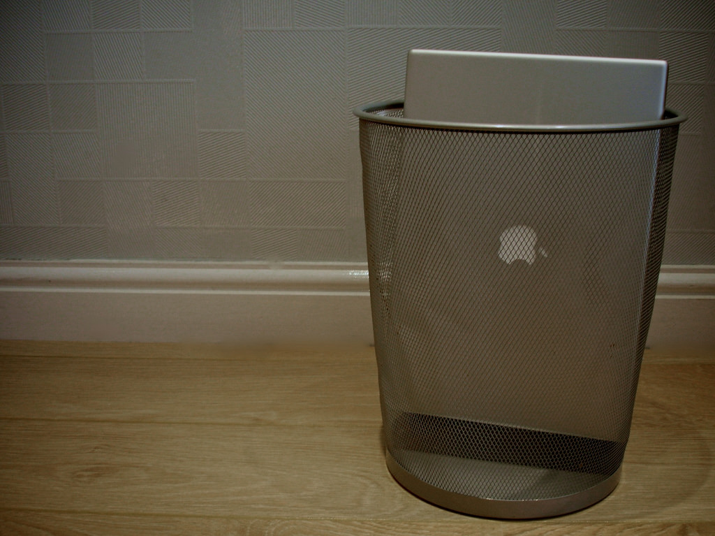 Photograph of a laptop placed in a trash reciptical